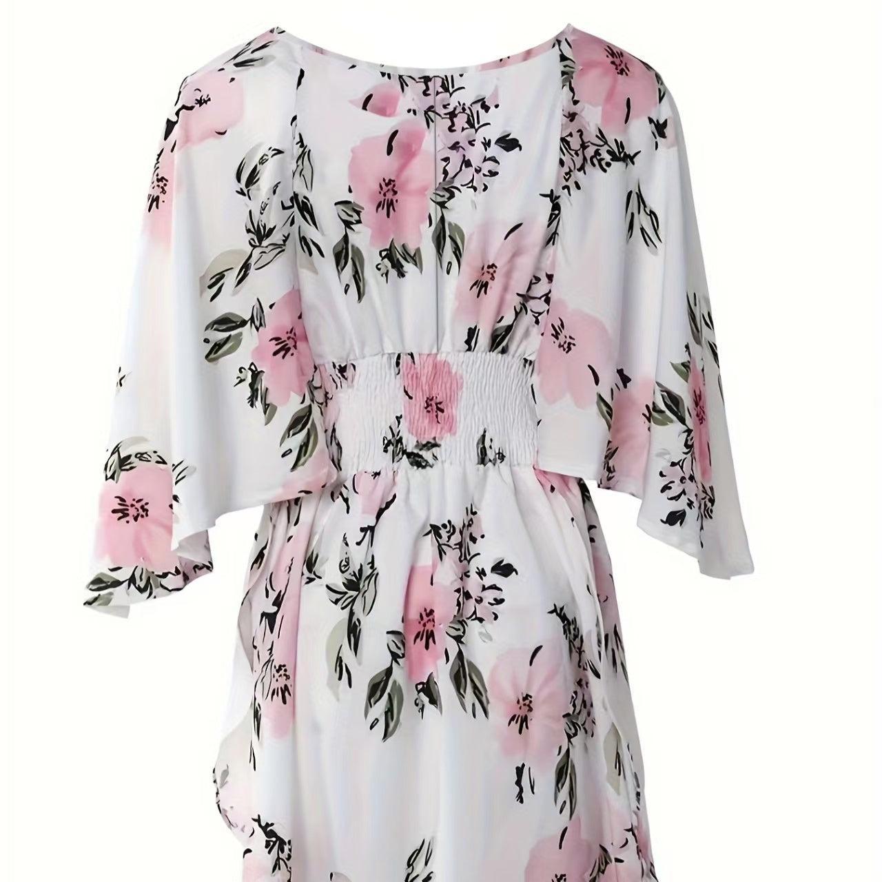 Woman wearing a white floral romper with wide kimono sleeves and pink flower print, featuring a smocked waist and V-neckline.